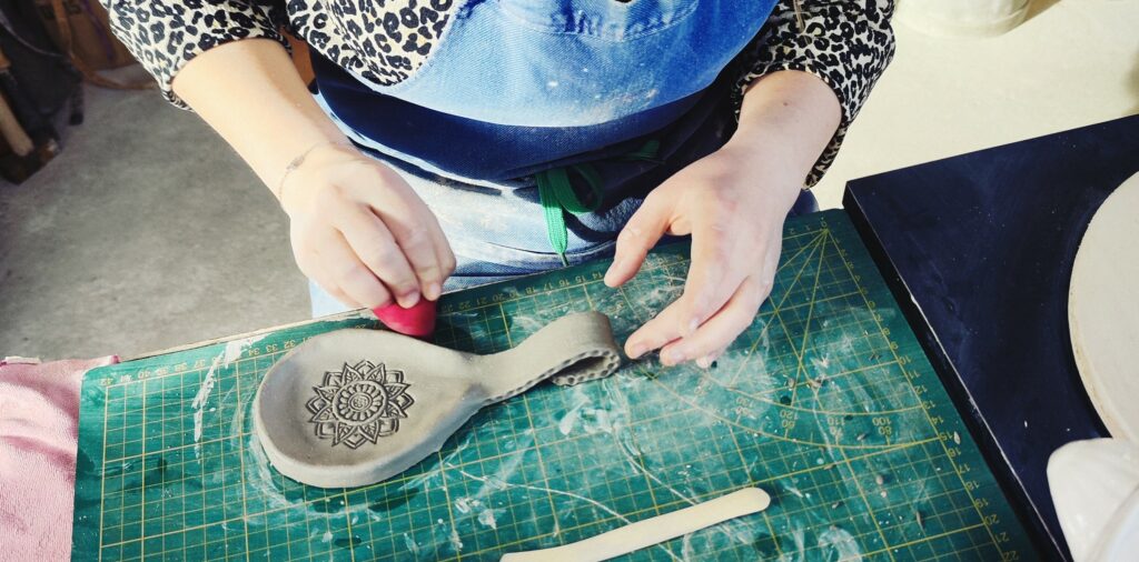 mains d'une personnes los d'un atelier façonnant un porte cuillère estampé d'un tampon des Indes.