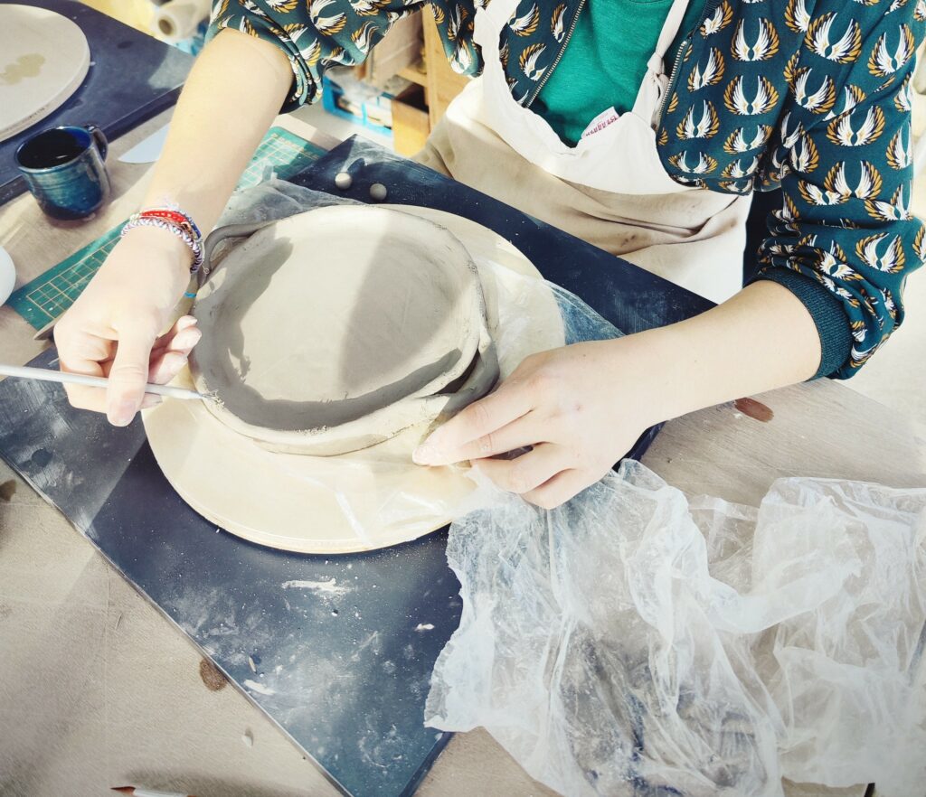 Plateau en terre agrémenté de petites poignées, réalisé par une personnes lors d'un atelier.