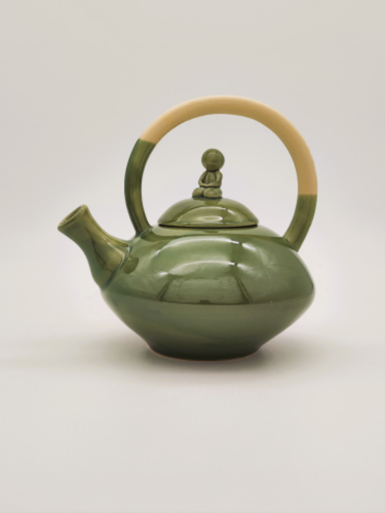 théière de forme ovale doté d'une anse panier avec un petit bonhomme en méditation sur le couvercle, émaillé en vert céladon jusqu'à la moitié de la anse.
Atelier terre de Djen
